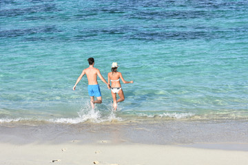 Back view of couple running into Caribbean water