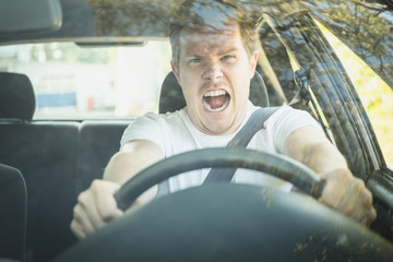 Wütender junger Mann sitzt im Auto