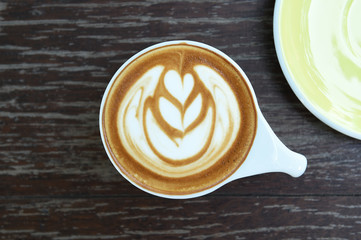 cup of latte art coffee on wooden background
