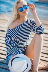 Beautiful Girl in sea style sitting on wooden bridge.