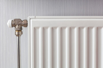 Heating white radiator with adjuster of warming in living room.