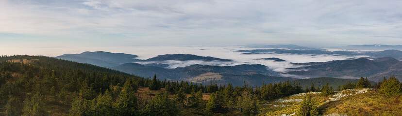 Naklejka na ściany i meble View from the autumn mountains into the valley with low clouds