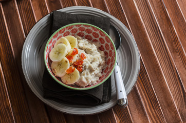 Oatmeal with banana  and dried apricots. On a dark wooden table. Healthy Breakfast