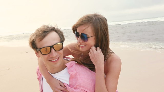 Smiling young man piggybacking his happy girlfriend on beach Oahu Hawaii