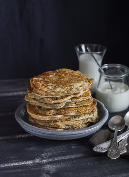 Healthy breakfast or snack - whole grain pancake, milk and cream on a dark wooden table