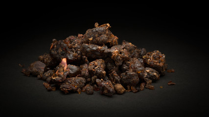 Pile of Organic Indian bdellium or Guggul resin (Commiphora wightii) on dark background.