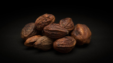 Pile of Organic Inknut or Harr (Terminalia chebula) on dark background.