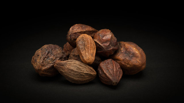 Pile of Organic Inknut or Harr (Terminalia chebula) on dark background.