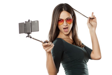 pretty brunette with sunglasses takes a selfies with monopod