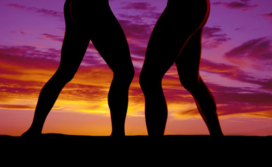 silhouette of two womens legs in the sunset