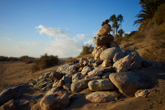 Heap of stones in desert / Sandy and stony dunes with stylish forms in a wide desert under blue sky