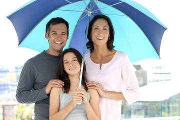 Happy family with one child standing under an umbrella during a heat wave 