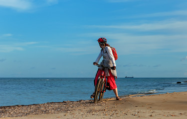 Young woman mountain bike stands on bank of Mediterranean Sea