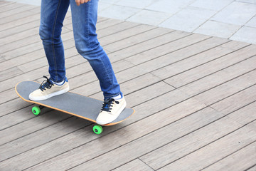 Fototapeta na wymiar woman skateboarder legs riding skateboard on wooden boardwalk