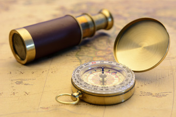 Old compass and old telescope on vintage map world explorer concept