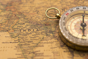 Fototapeta na wymiar Old compass on vintage map selective focus on India