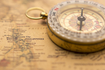 Old compass on vintage map selective focus on Philippines