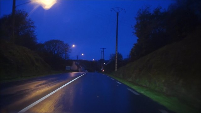 Fahrt mit dem PKW &uuml;ber eine Landstra&szlig;e in der blauen Stunde 