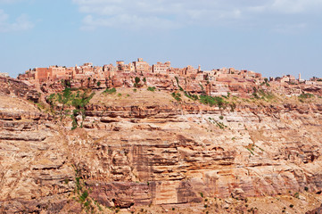 Fototapeta na wymiar Rocce rosse, montagna, le antiche mura e le case decorate della città fortificata di Kawkaban, Yemen
