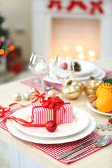 Christmas table setting with holiday decorations on fireplace background
