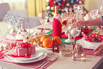 Woman hand lights a candle on holiday table setting