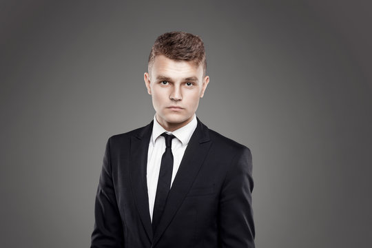 Portrait of young trendy groom with black tie on gray background