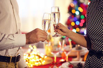Man and woman clanging champagne glasses on Christmas background