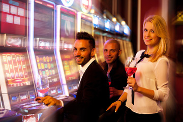 four young people playing slot machines in casino