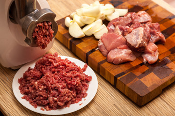 The electric meat grinder, forcemeat, onions and the cut meat