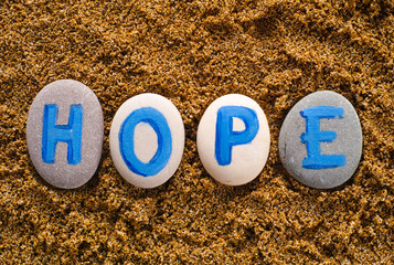 Word Hope spell out from stones with letters on sea sand. Letters drawn by me