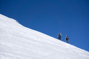 Snowboarders walking uphill for freeride