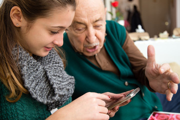 Nipote che insegna l'uso dello smartphone al nonno