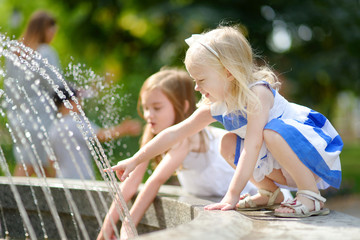 Two cute little girls playing with a city fountain © MNStudio