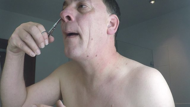 Mann k&uuml;rzt seine Haare in der Nase