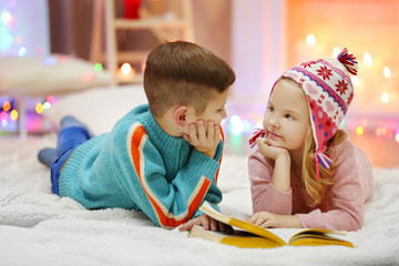 Cute children read book on the floor in the decorated Christmas room