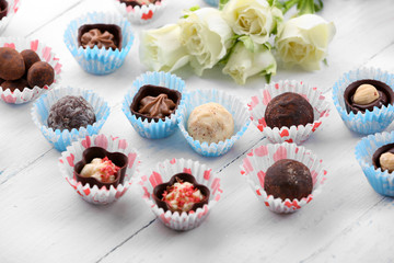 Set of chocolate candies with flowers on a light wooden background