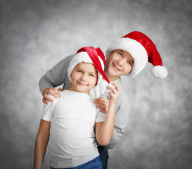 Obraz premium Brothers in Santa hats have fun on grey background