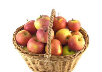 Brown wicker basket full of ripe selected apples isolated on white closeup