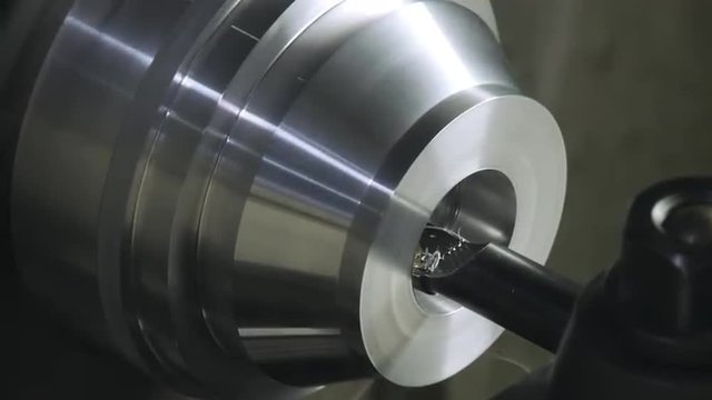 Detail of a CNC lathe in operation, cutting a metal part.