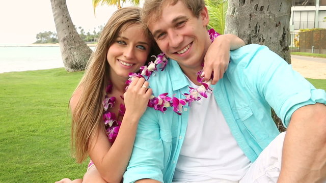 Portrait of a happy and romantic young couple wearing flower Lei on beach Oahu Hawaii.