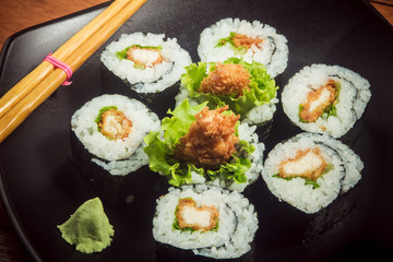Japanese roll with chicken and lettuce on the black plate