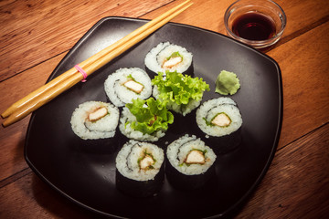 Japanese roll with chicken and lettuce on the black plate