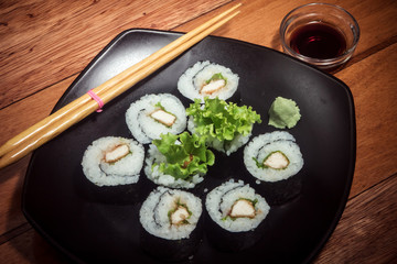 Japanese roll with chicken and lettuce on the black plate