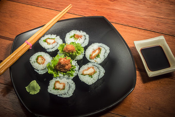 Japanese roll with chicken and lettuce on the black plate