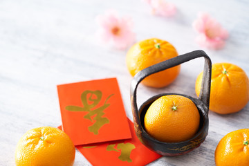 Chinese New Year - Mandarin orange and red packet (Foreign text means spring season) on white painted wood table