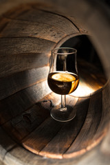 A glass of whiskey on a background of oak barrels