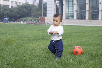 Fototapeta premium Cute Chinese baby boy playing soccer in meadow