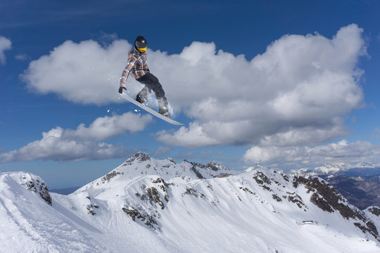 Flying snowboarder on mountains. Extreme sport.