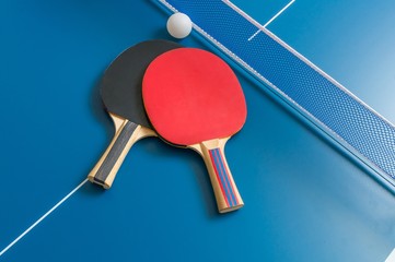 Ping pong rackets and table tennis net on wooden table - obrazy, fototapety, plakaty