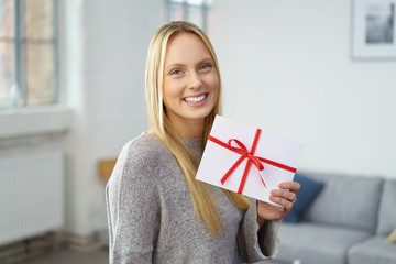 lächelnde frau mit einem geschenk-gutschein in ihrer wohnung